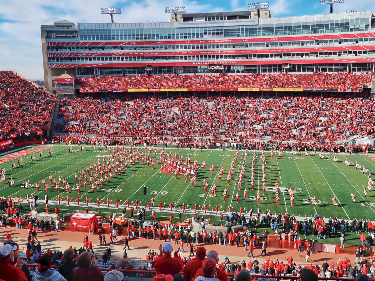 Nebraska Cornhuskers football stadium packed with fans in red, with players lined up on the field before kickoff.