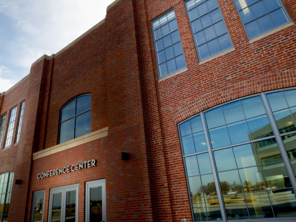 A red-brick building with glass windows labeled &ldquo;CONFERENCE CENTER&rdquo; and entrance doors.